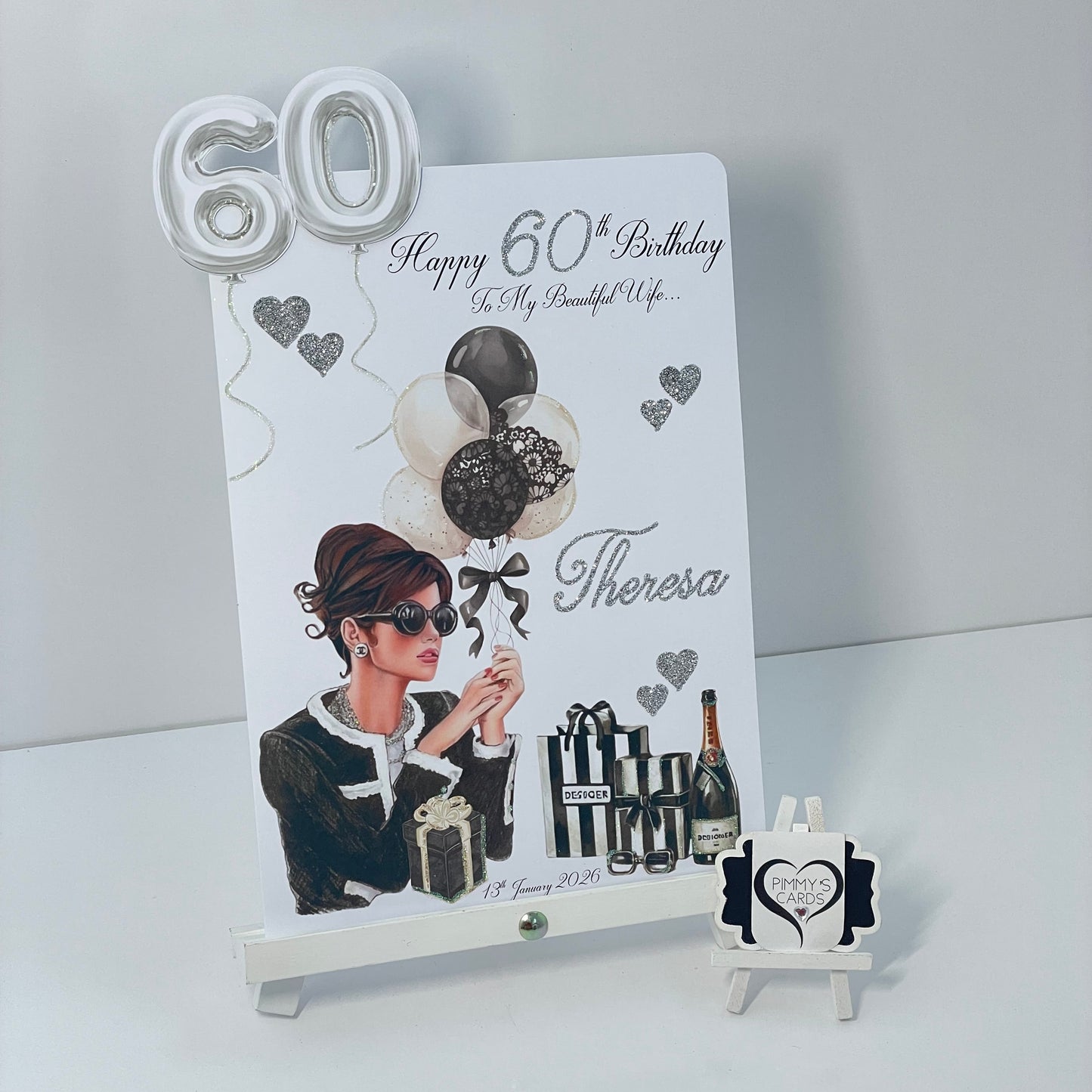 60th birthday card with illustration of a woman, balloons, and personalized text on a white stand.